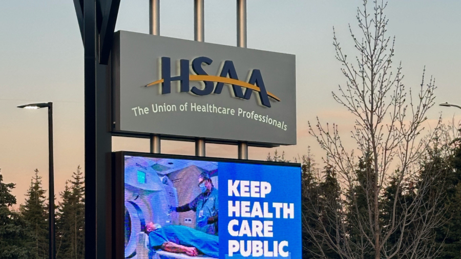 A sign outside the HSAA office with the logo and a digital screen that says "Keep Health Care Public"