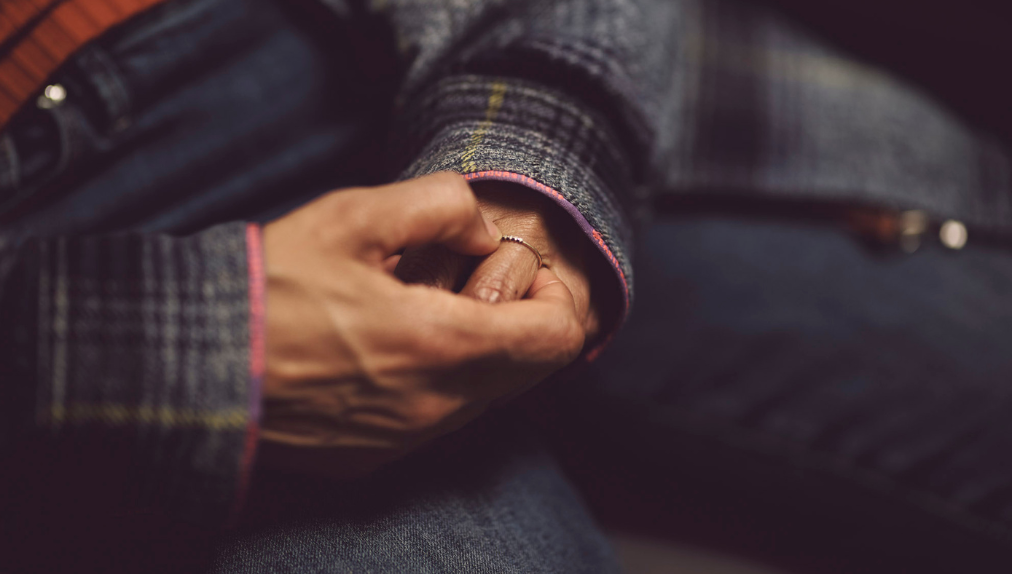 A close up of someone clasping their hands and twisting a ring on their finger.