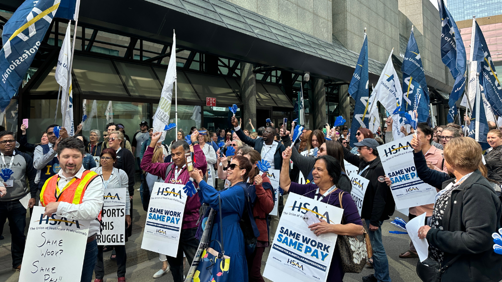 A crowd of members with HSAA signs and flags, rallying outside DynaLIFE headquarters.