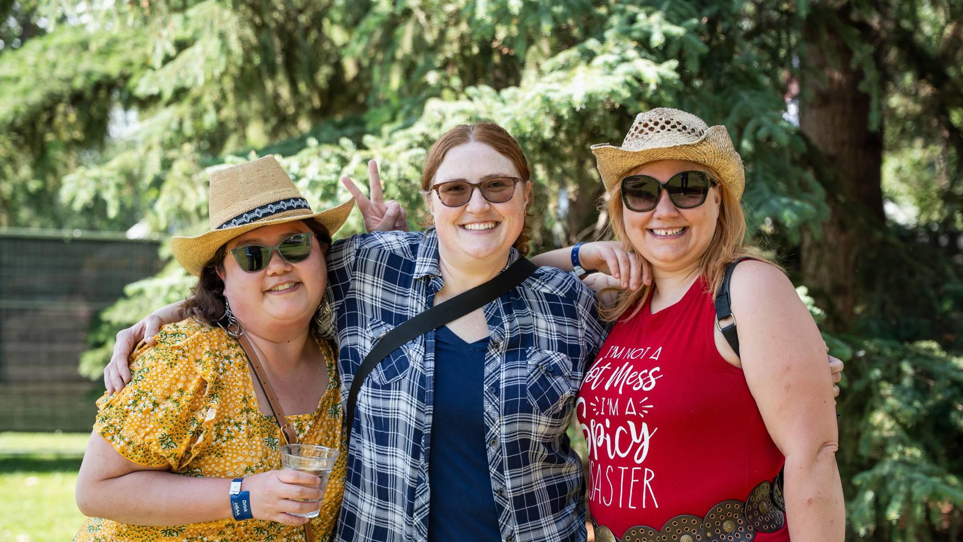 Three people smiling together for a photo at the Round Up Music Fest Event.