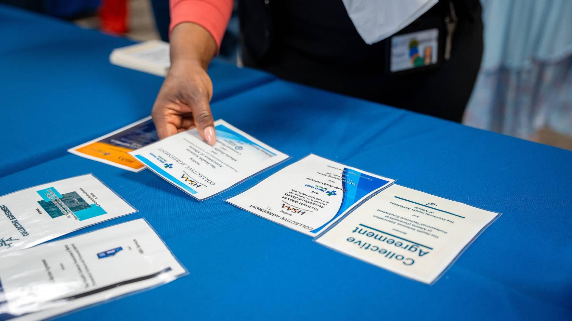 Images of collective agreement covers on a table as a hand grabs and places one in order.